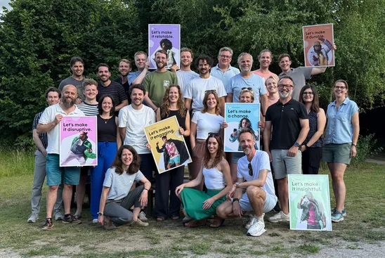 Groepsfoto van Awareways team in de buitenlucht, terwijl sommigen een lijst omhoog houden met merkidentiteit elementen.